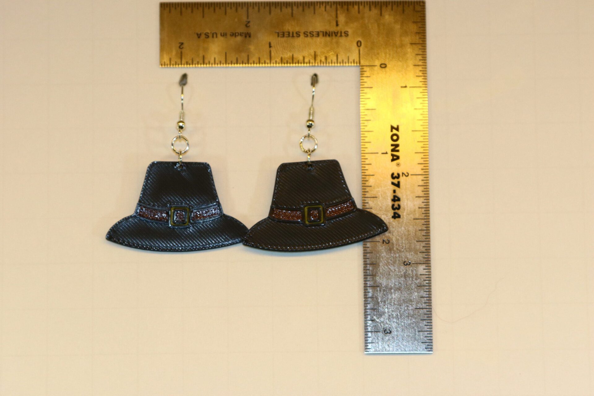 Pair of earrings shaped like black pilgrim hats with gold buckles.