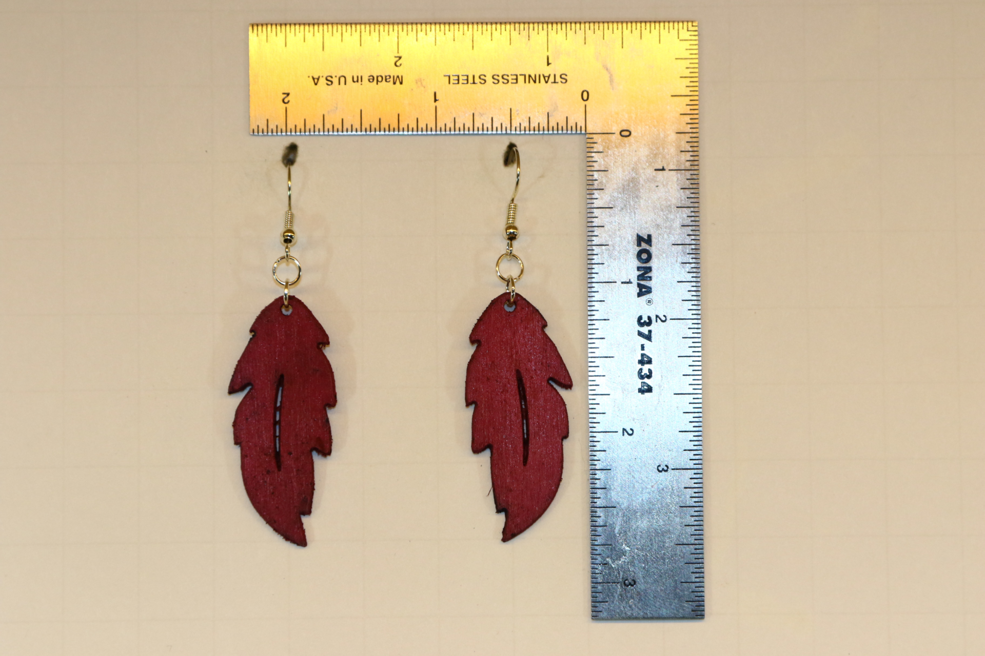 Wooden feather earrings with detailed carved feather design.