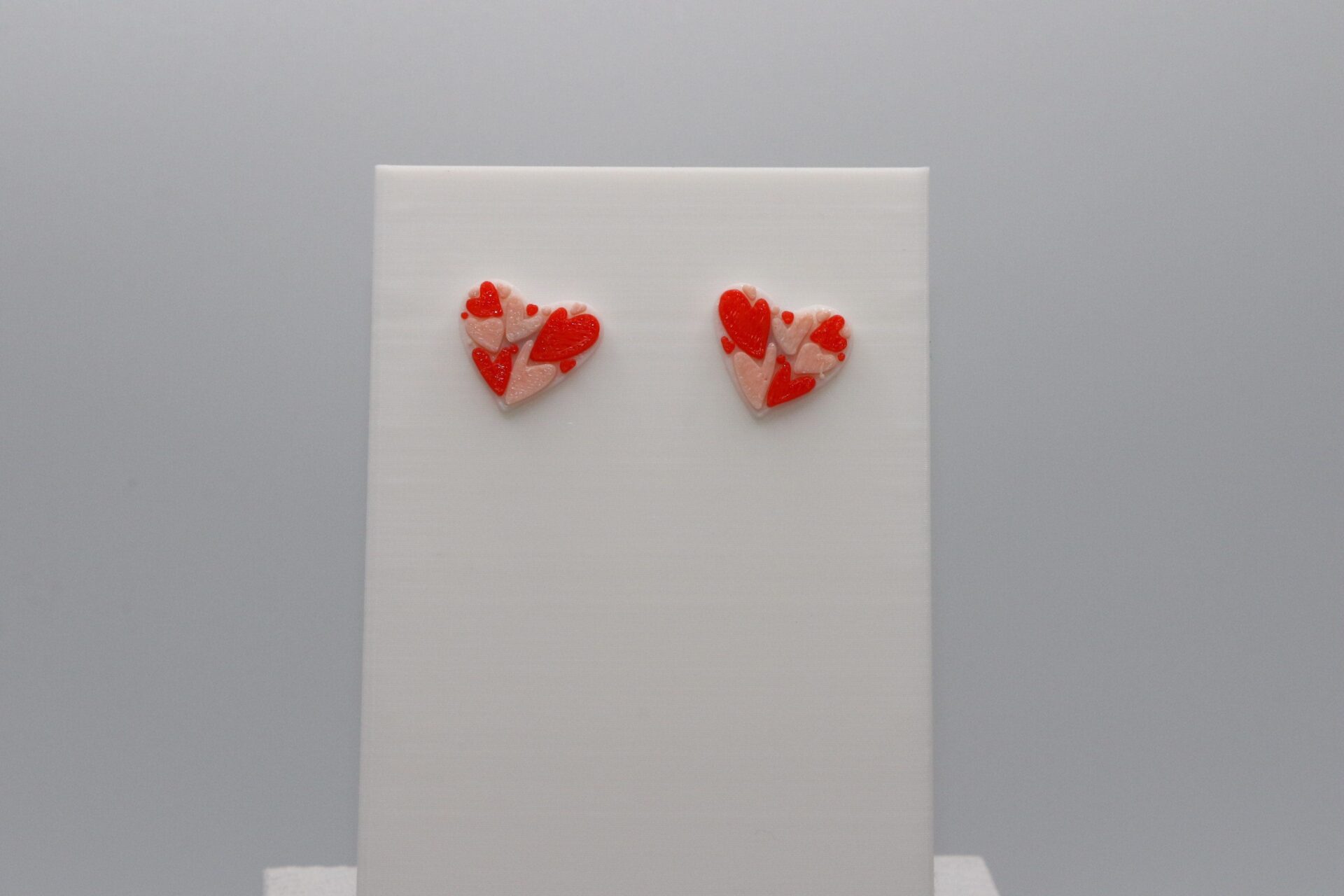 Pair of stud earrings featuring nested layered heart designs.