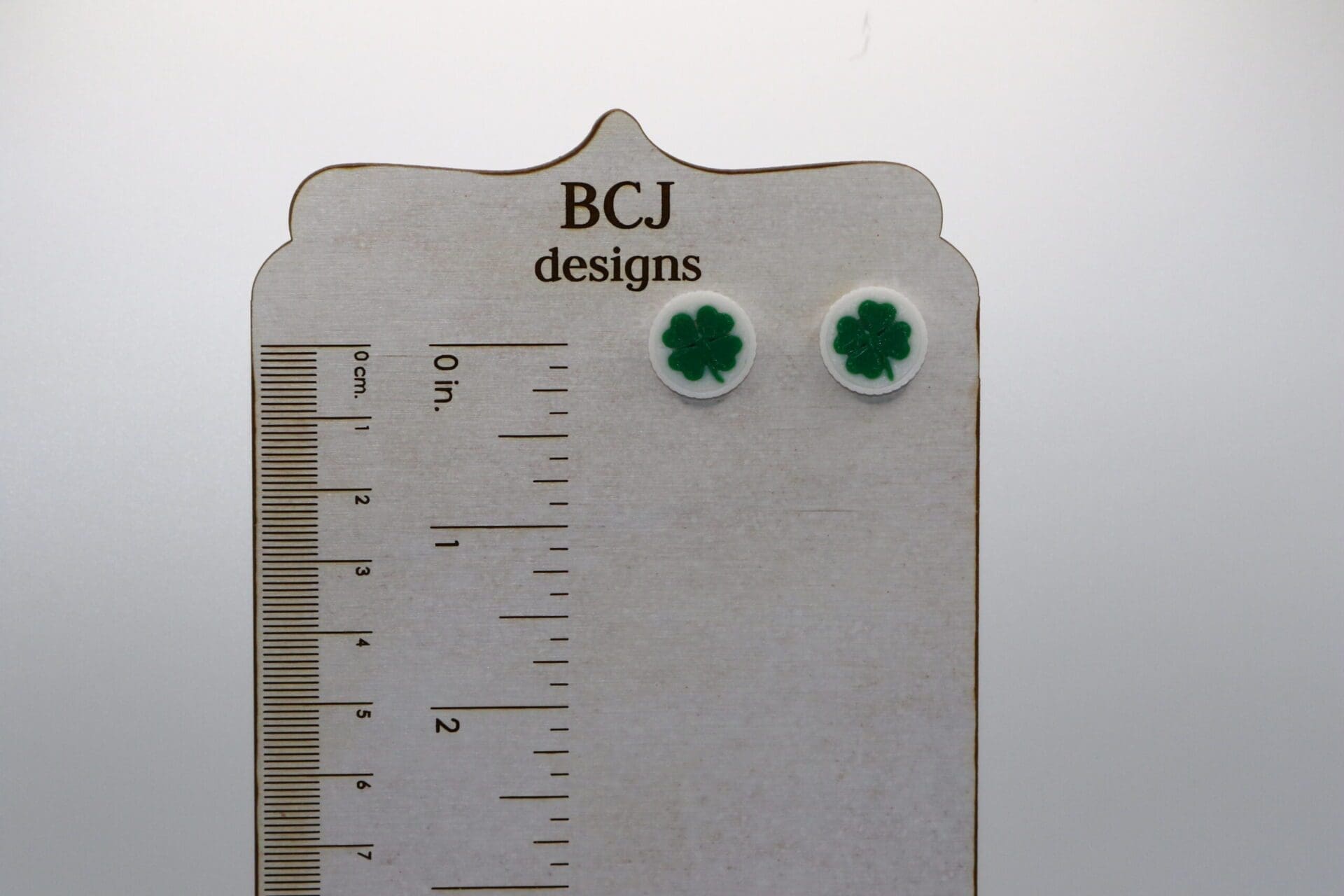 Pair of small stud earrings featuring green clover medallions.