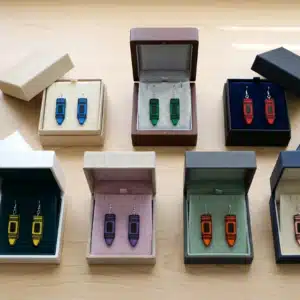 Crayon earrings in boxes on a desk.