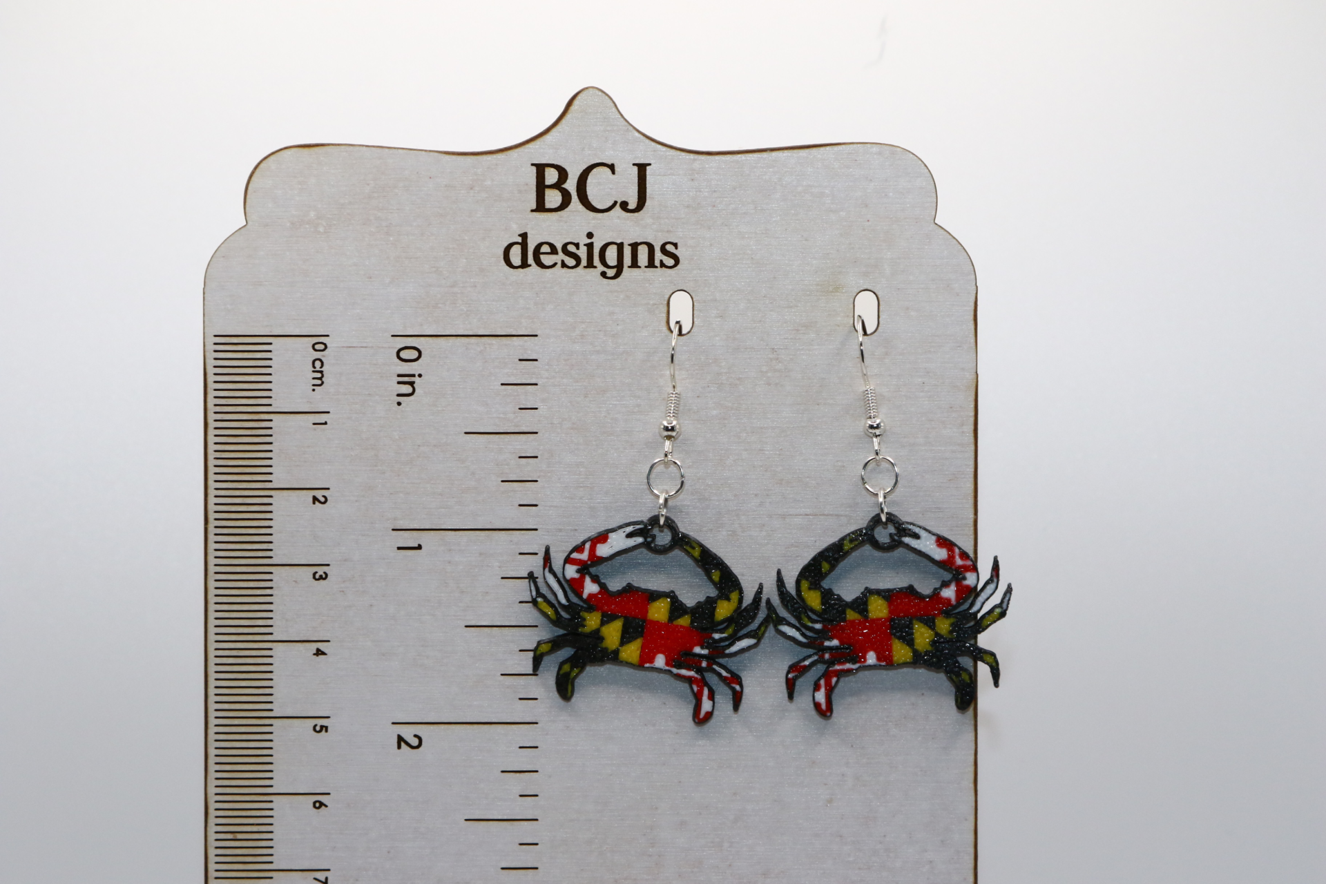Maryland flag crab earrings with red, yellow, and black pattern.