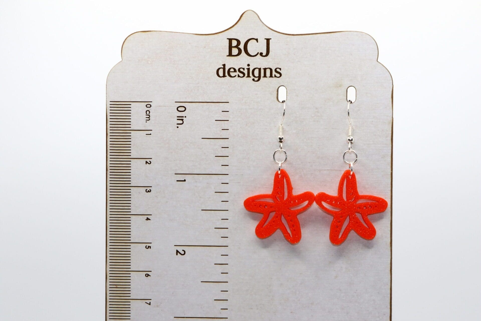 Pair of earrings shaped like detailed starfish in natural colors.