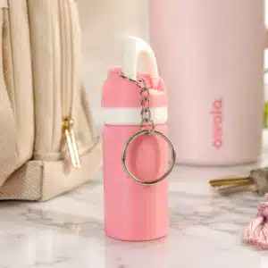 Pink personalized Owala bottle keychain displayed on a marble countertop beside a matching tumbler, tote bag, and keys for a stylish everyday carry setup.