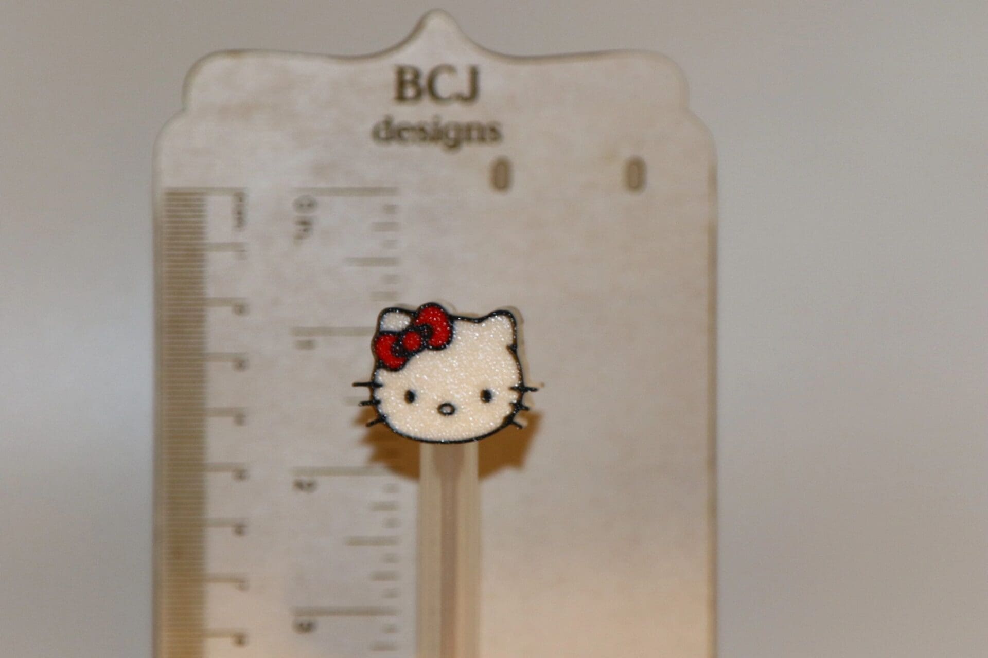 Hello Kitty straw topper with white face and red bow.