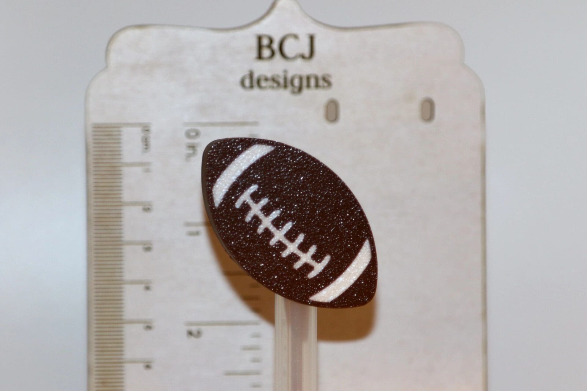 Football-shaped straw topper attached to a drinking straw