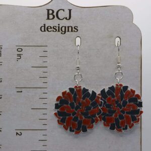 Orange and black pompom earrings representing Rising Sun High School