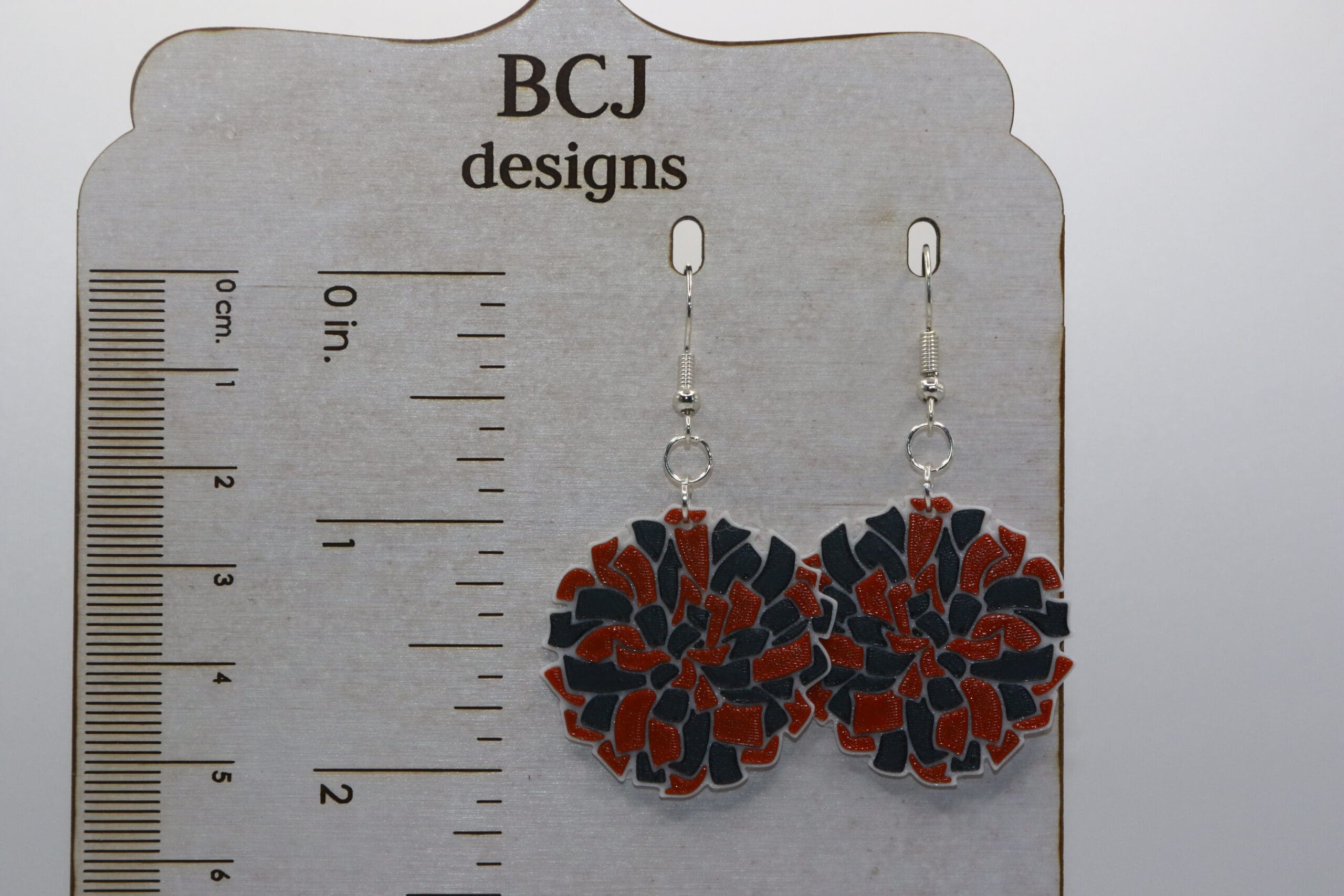 Orange and black pompom earrings representing Rising Sun High School