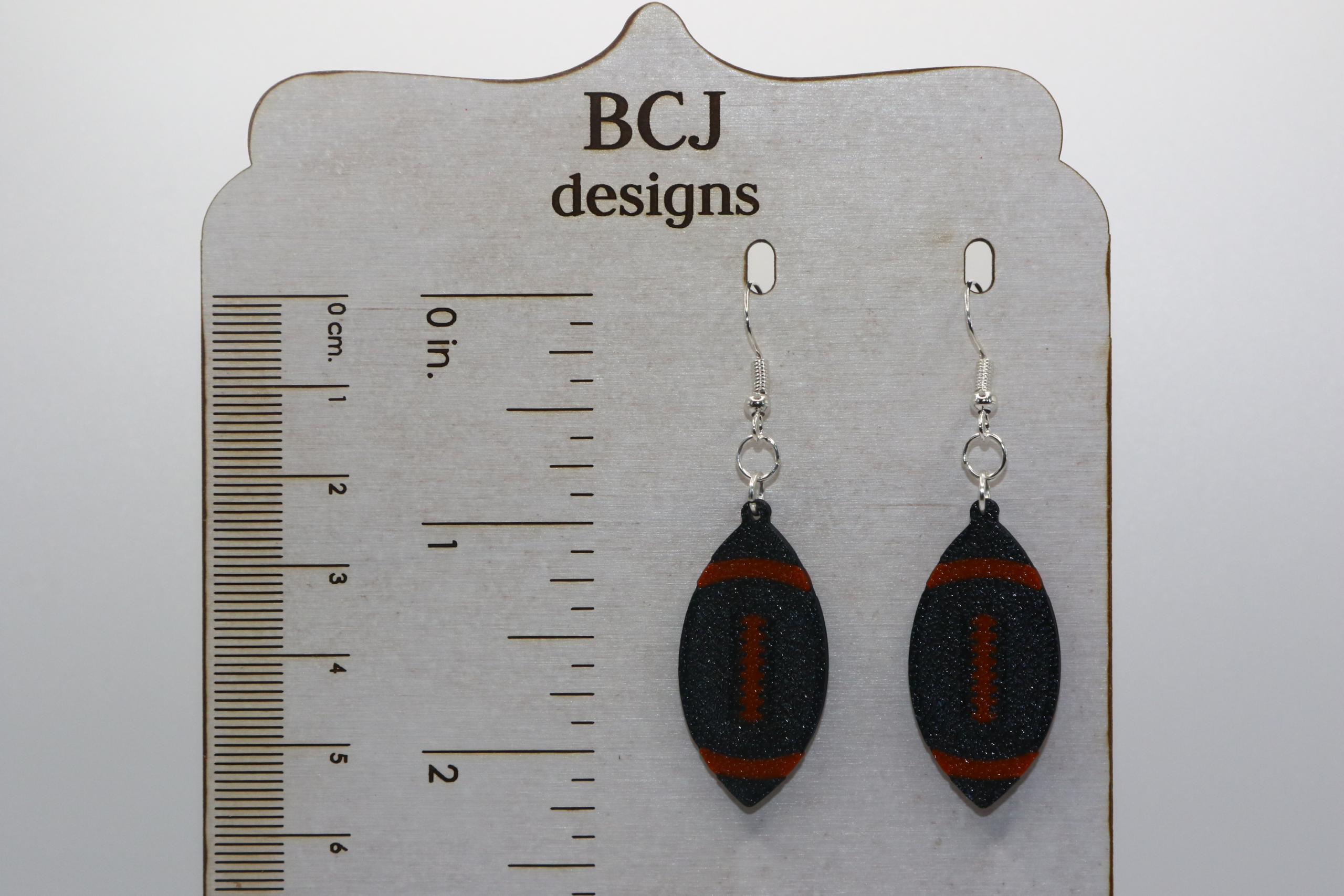Black and orange football earrings representing Rising Sun High School spirit