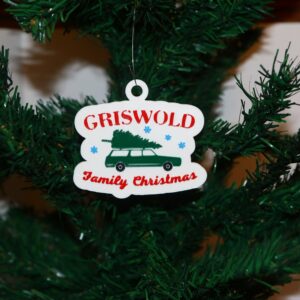 Griswold Christmas ornament featuring car with tree on roof, colorful holiday design.