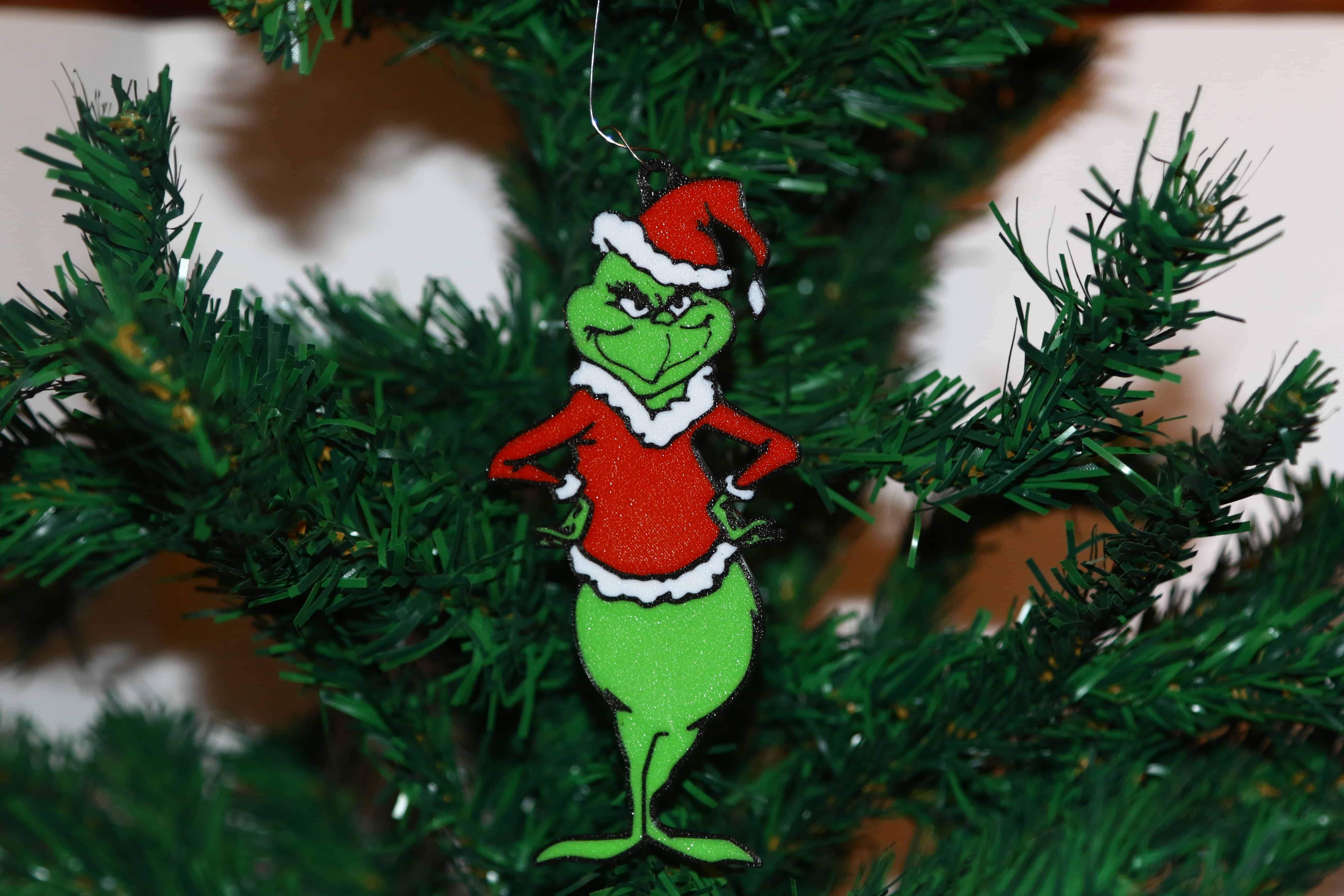 Grinch Christmas ornament with arms on hips, angry expression, green and red colors.