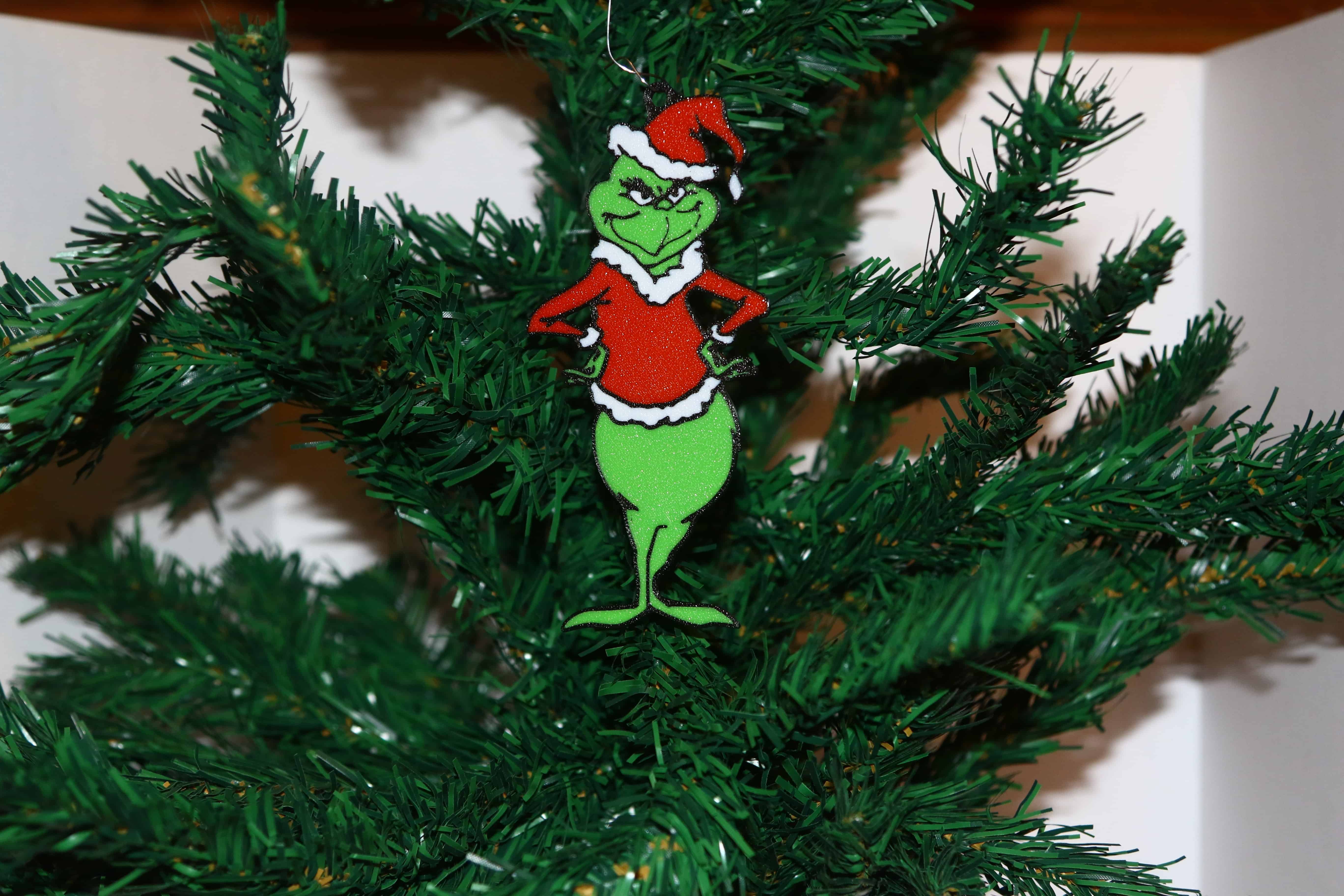 Grinch Christmas ornament with arms on hips, angry expression, green and red colors.