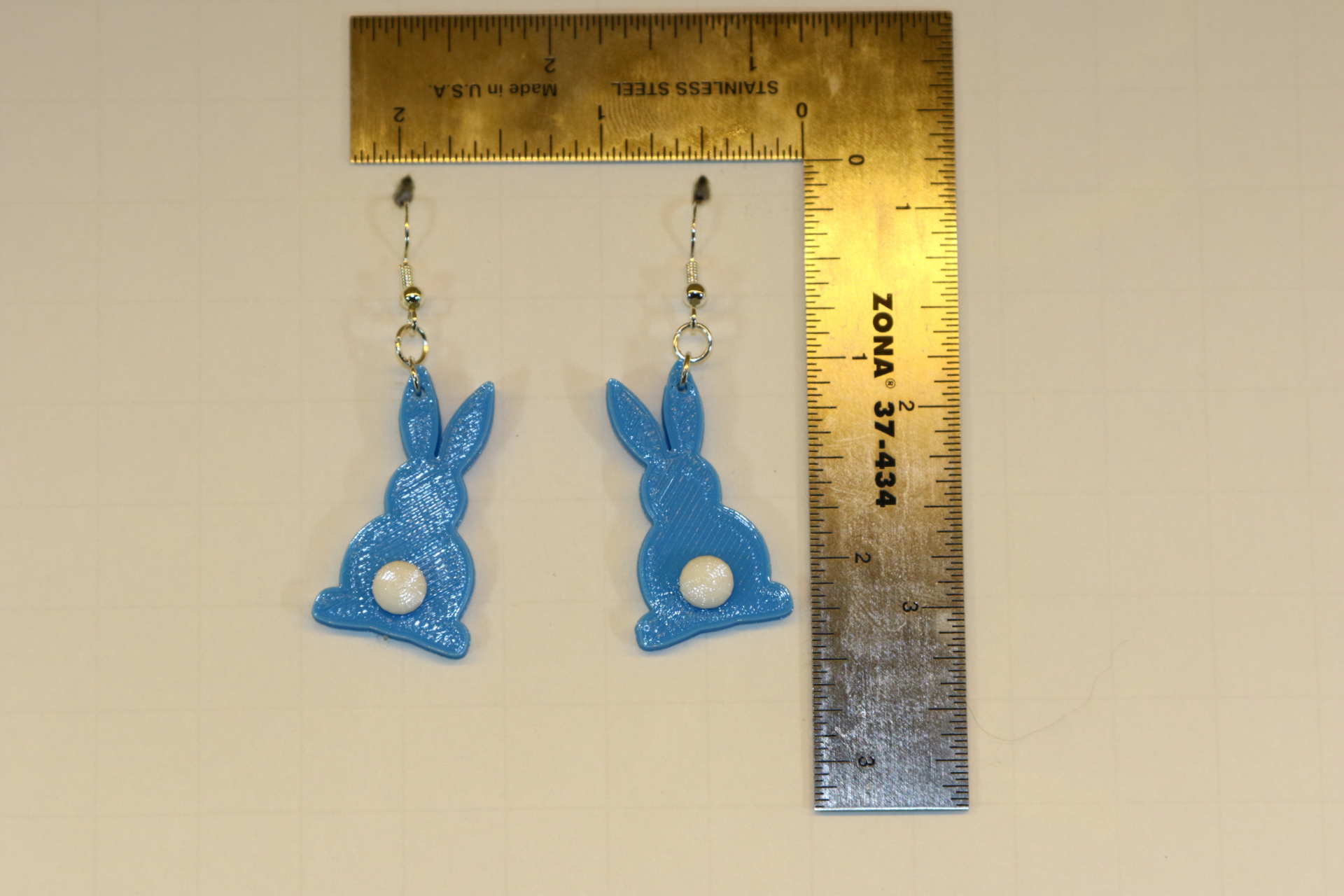 Bunny-shaped earrings featuring small fluffy tail accents.