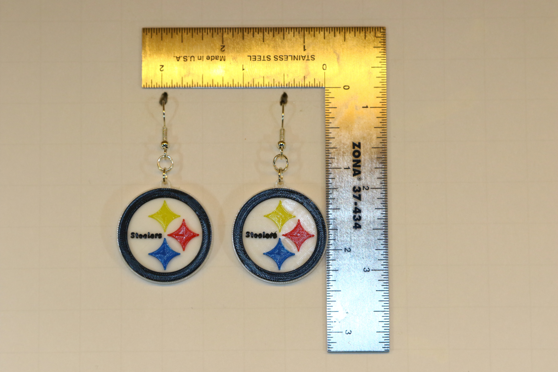 Pair of earrings featuring the Pittsburgh Steelers logo in black, gold, and white.