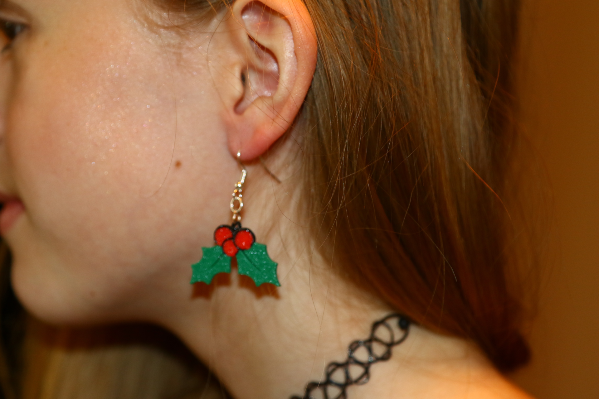 Pair of holly berry earrings with green leaves and red berries.