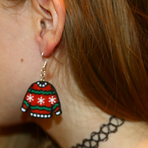 Pair of miniature ugly sweater earrings with colorful patterns.