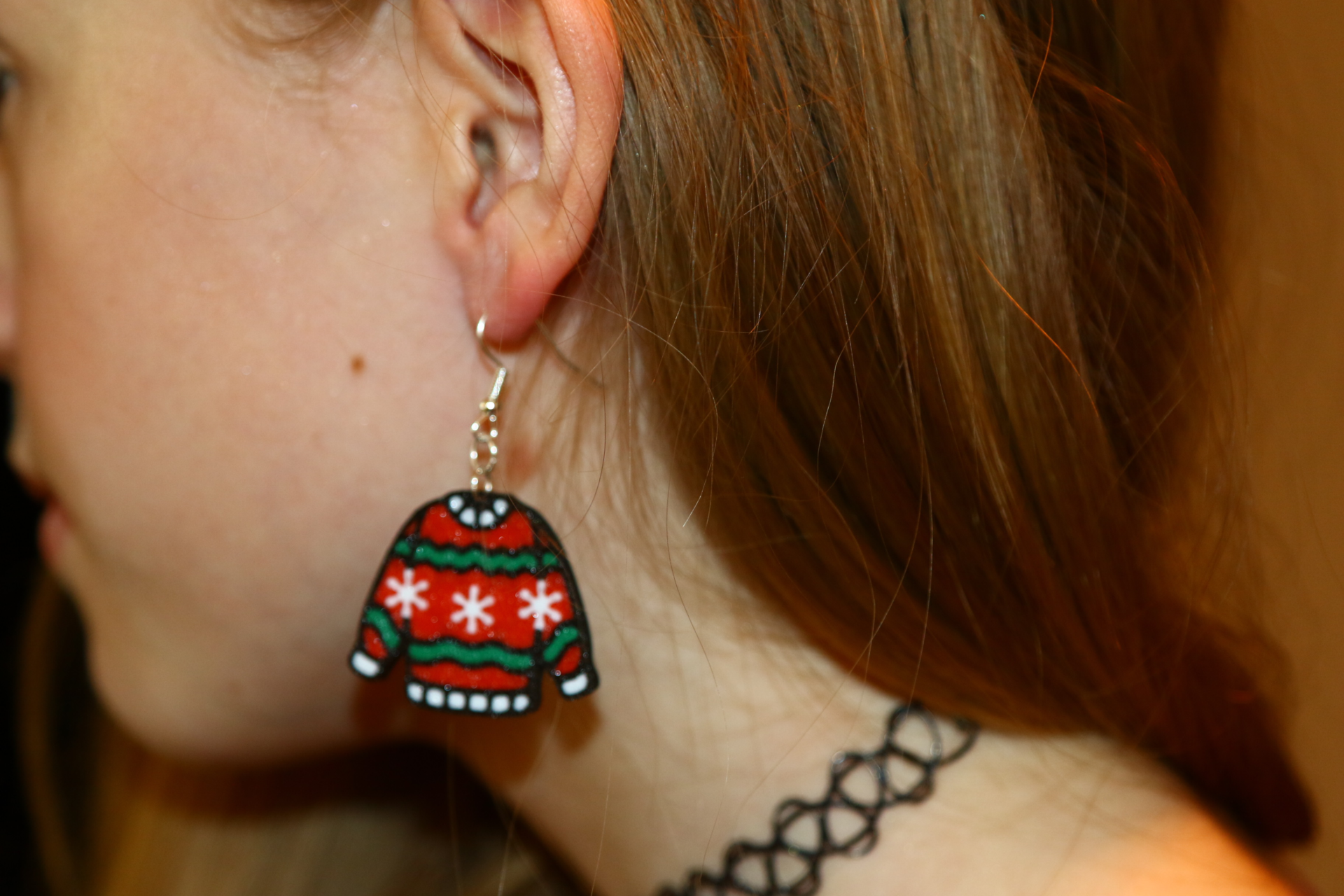 Pair of miniature ugly sweater earrings with colorful patterns.