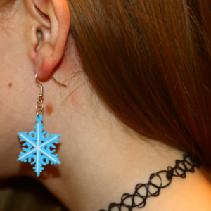 Pair of silver snowflake Christmas earrings with intricate detailing.