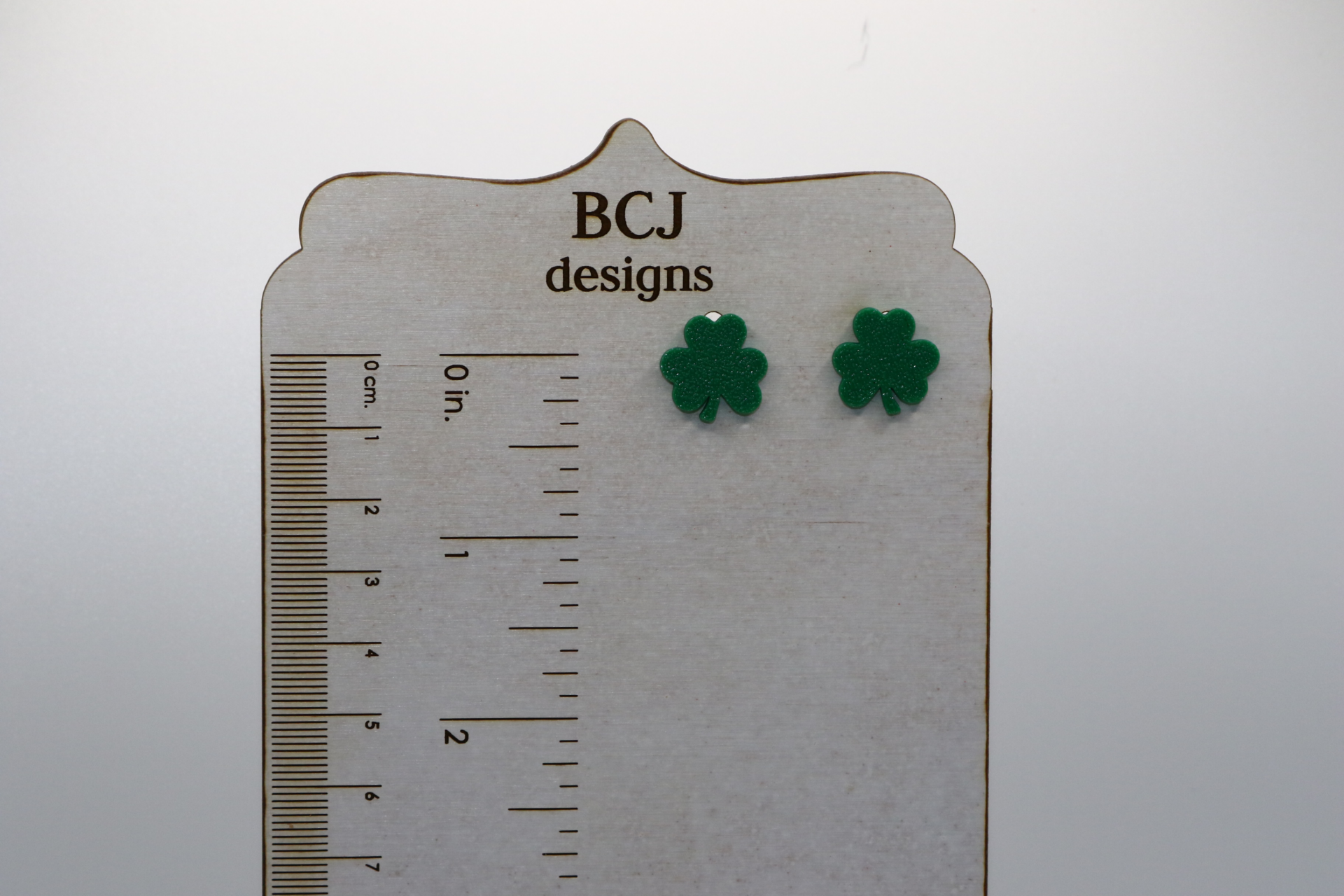 Pair of small stud earrings shaped like green shamrocks.