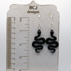 Pair of black snake earrings coiled with sleek detailing and silver hooks.