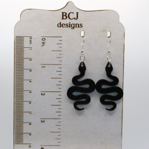 Pair of black snake earrings coiled with sleek detailing and silver hooks.