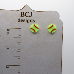 Pair of small stud earrings shaped like a yellow softball with red stitching.