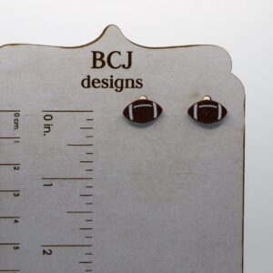 Pair of small stud earrings shaped like a brown football with white stitching.