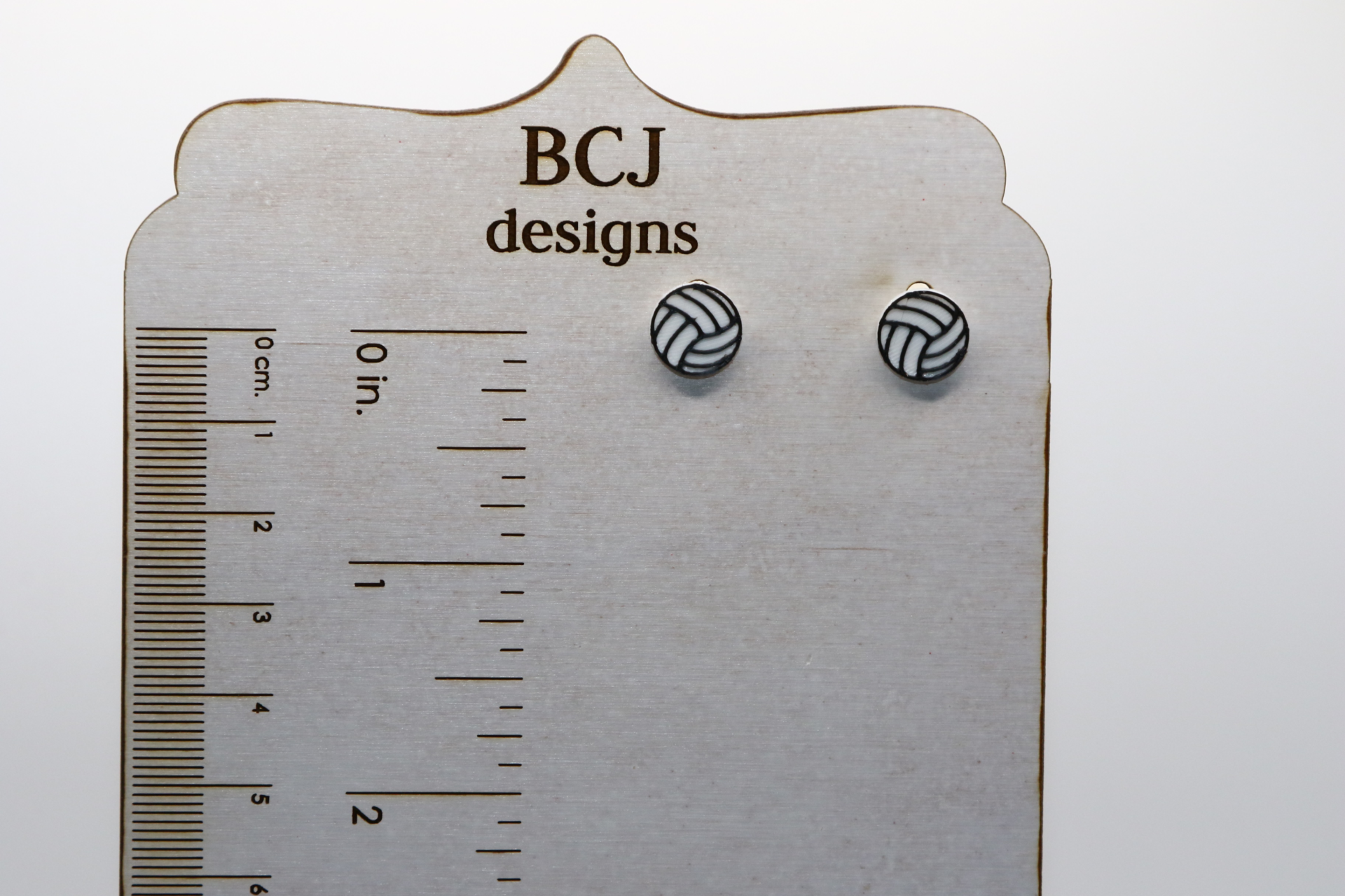 Pair of small stud earrings shaped like a volleyball.