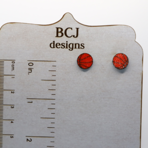 Pair of small stud earrings shaped like an orange basketball with black lines.