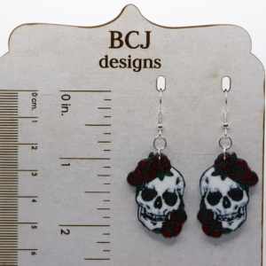Skull-shaped earrings adorned with red roses for Cinco de Mayo.