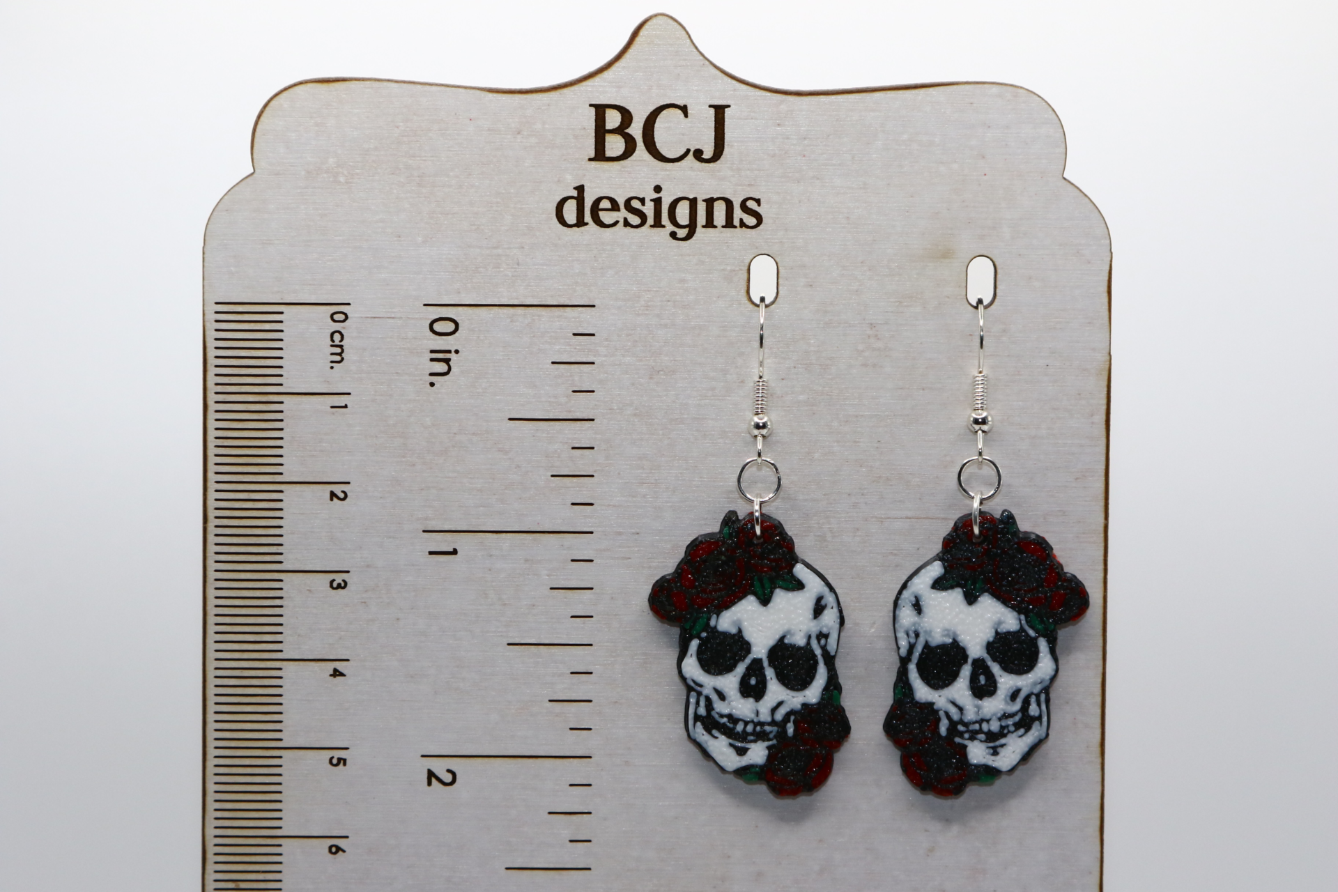 Skull-shaped earrings adorned with red roses for Cinco de Mayo.