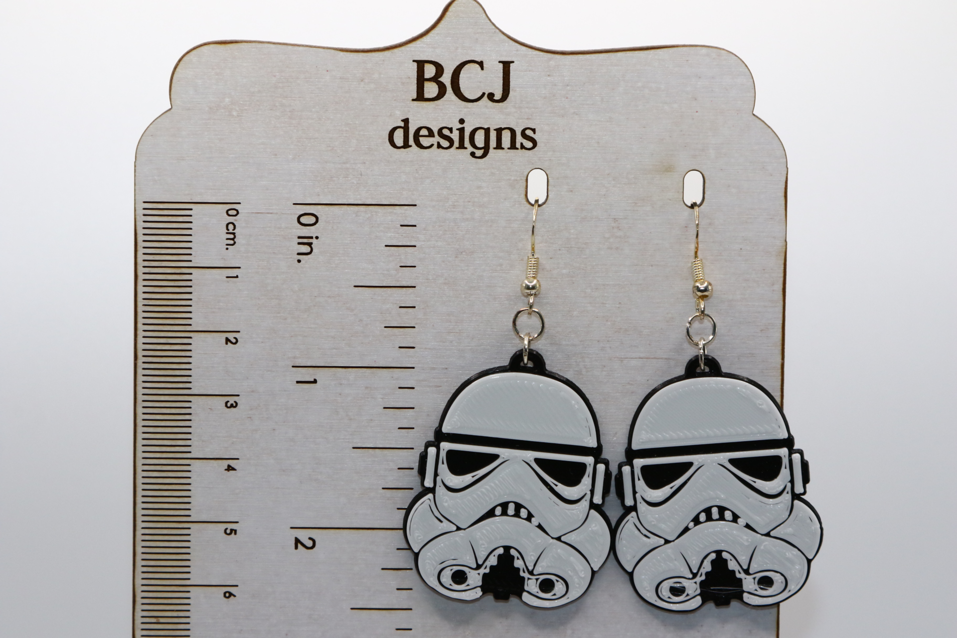 Pair of white Stormtrooper helmet earrings with black detailing.