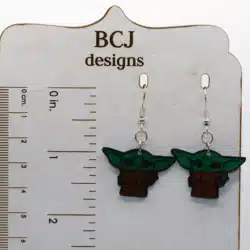 Pair of green Baby Yoda earrings with big ears and bright eyes.
