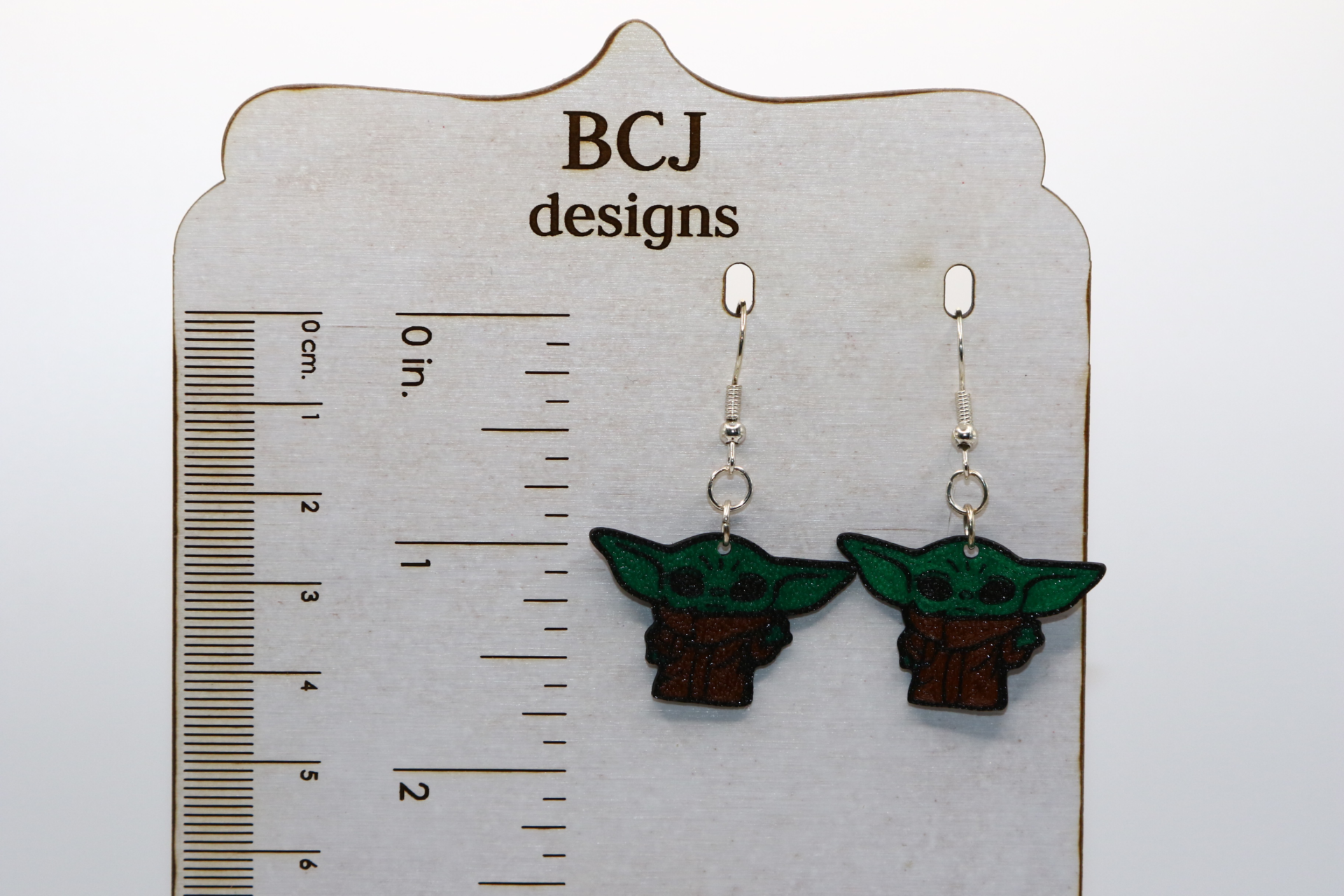 Pair of green Baby Yoda earrings with big ears and bright eyes.