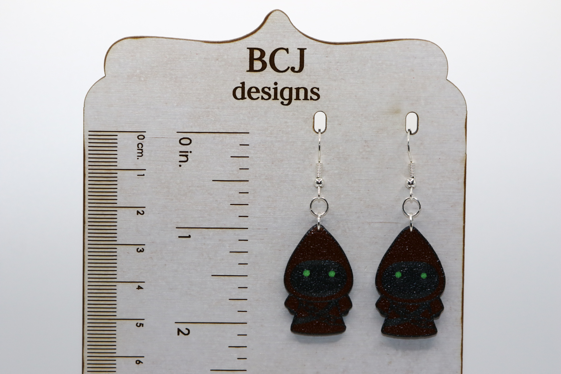 Pair of earrings shaped like small hooded Jawas with glowing yellow eyes.