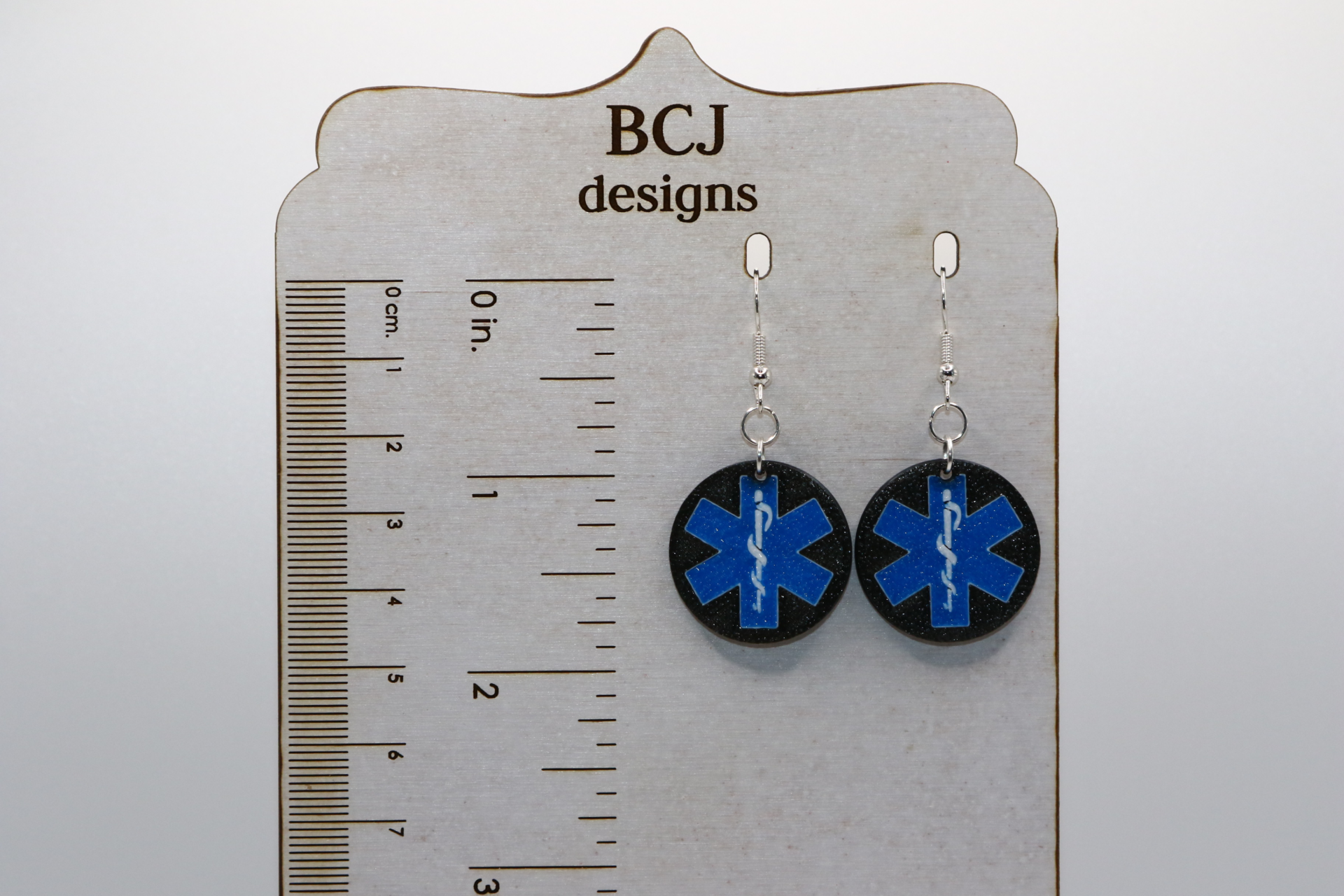 Pair of earrings featuring symbols representing police, fire, and medical first responders.