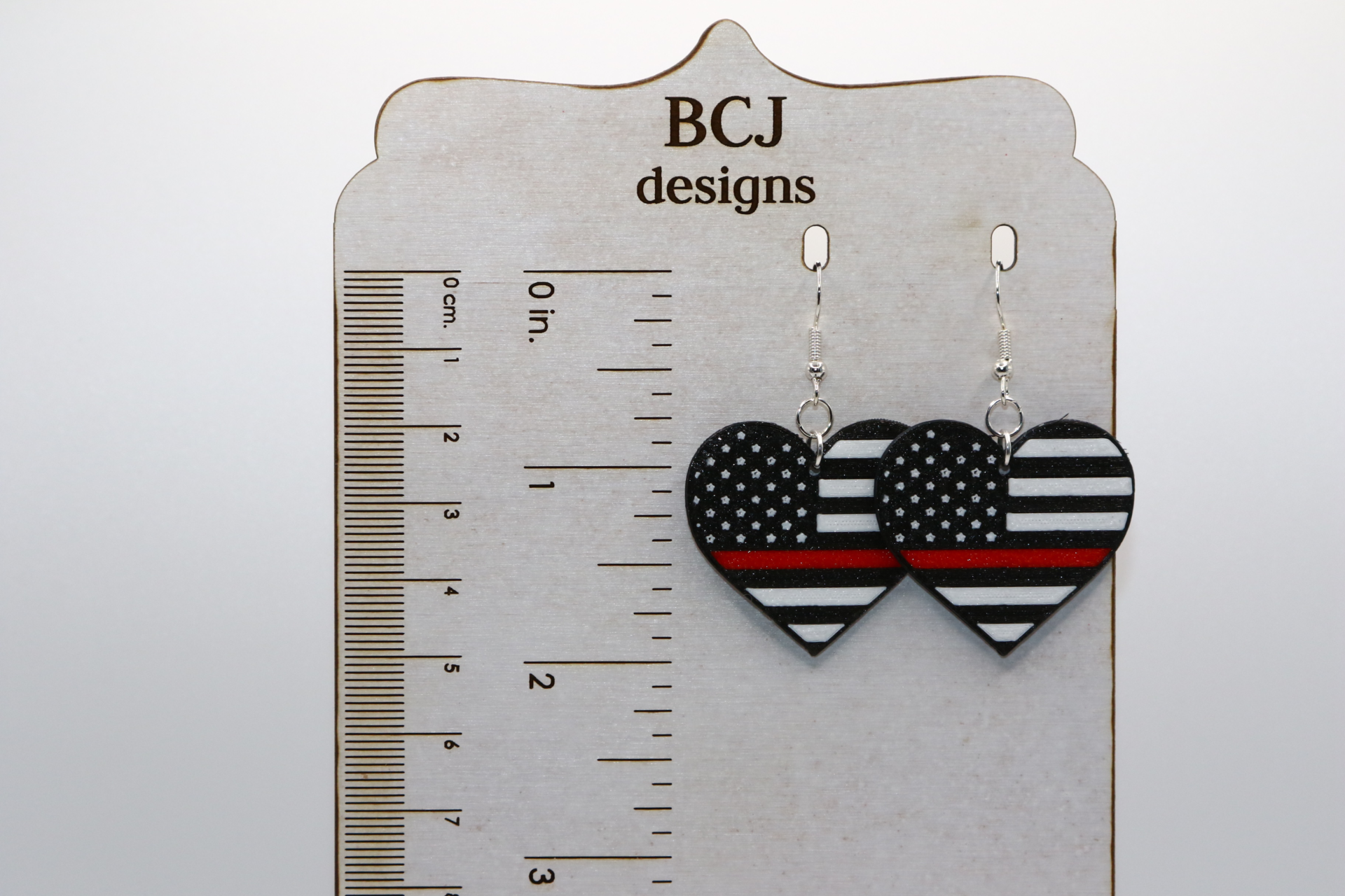 Heart-shaped earrings featuring black and white flag with thin red line.