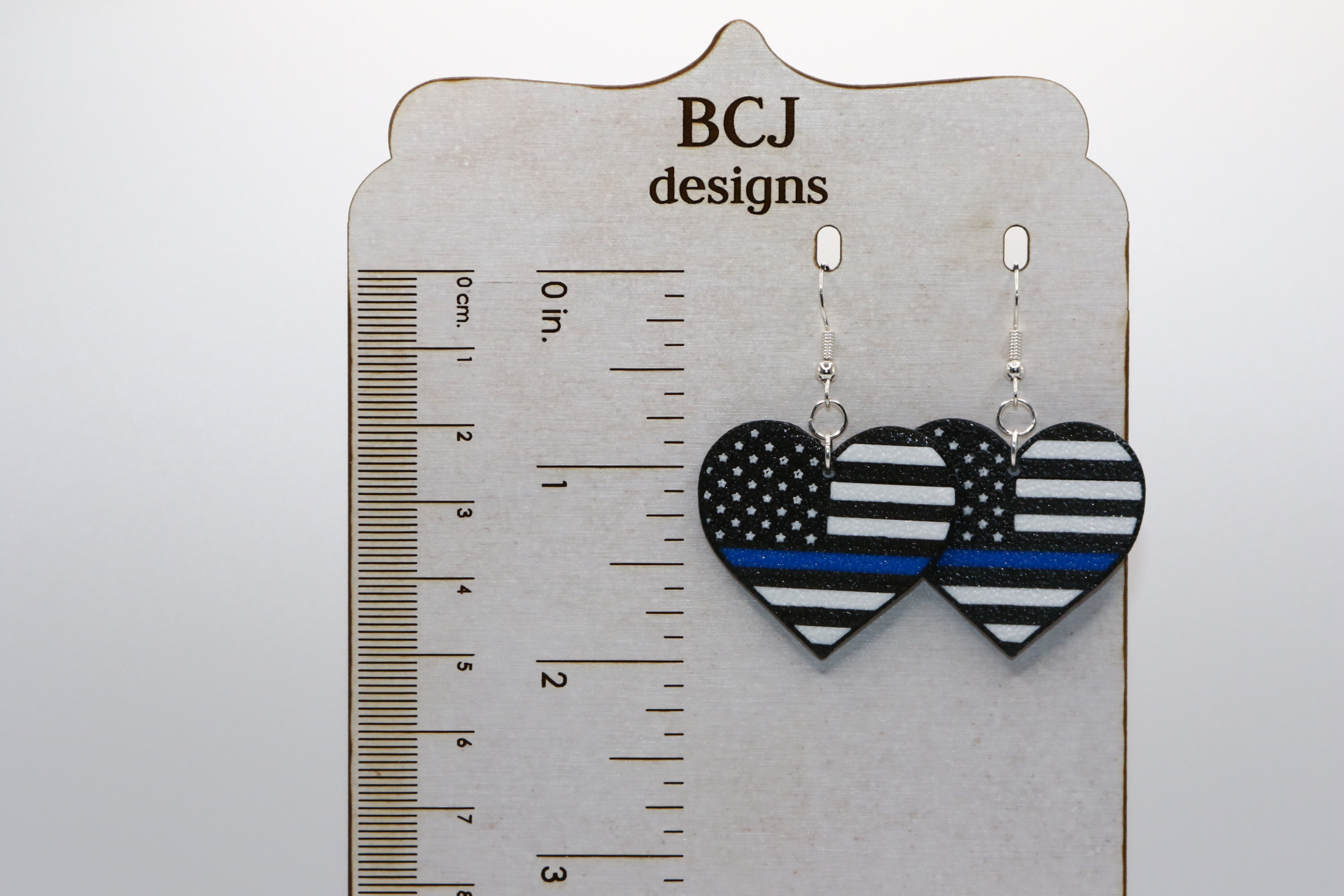 Heart-shaped earrings with black and white flag featuring thin blue line.