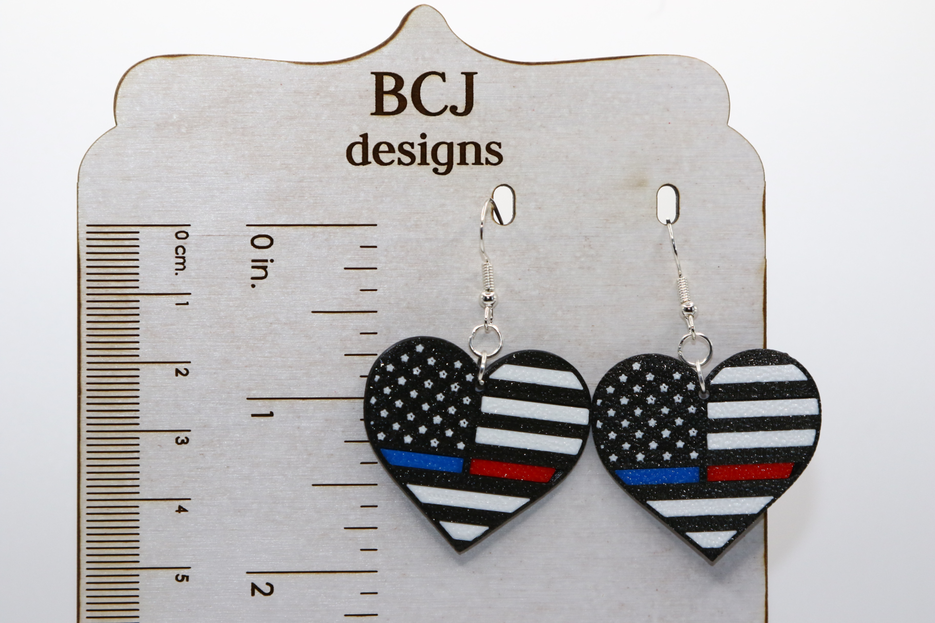 Heart-shaped earrings featuring American flag with thin red and blue line.