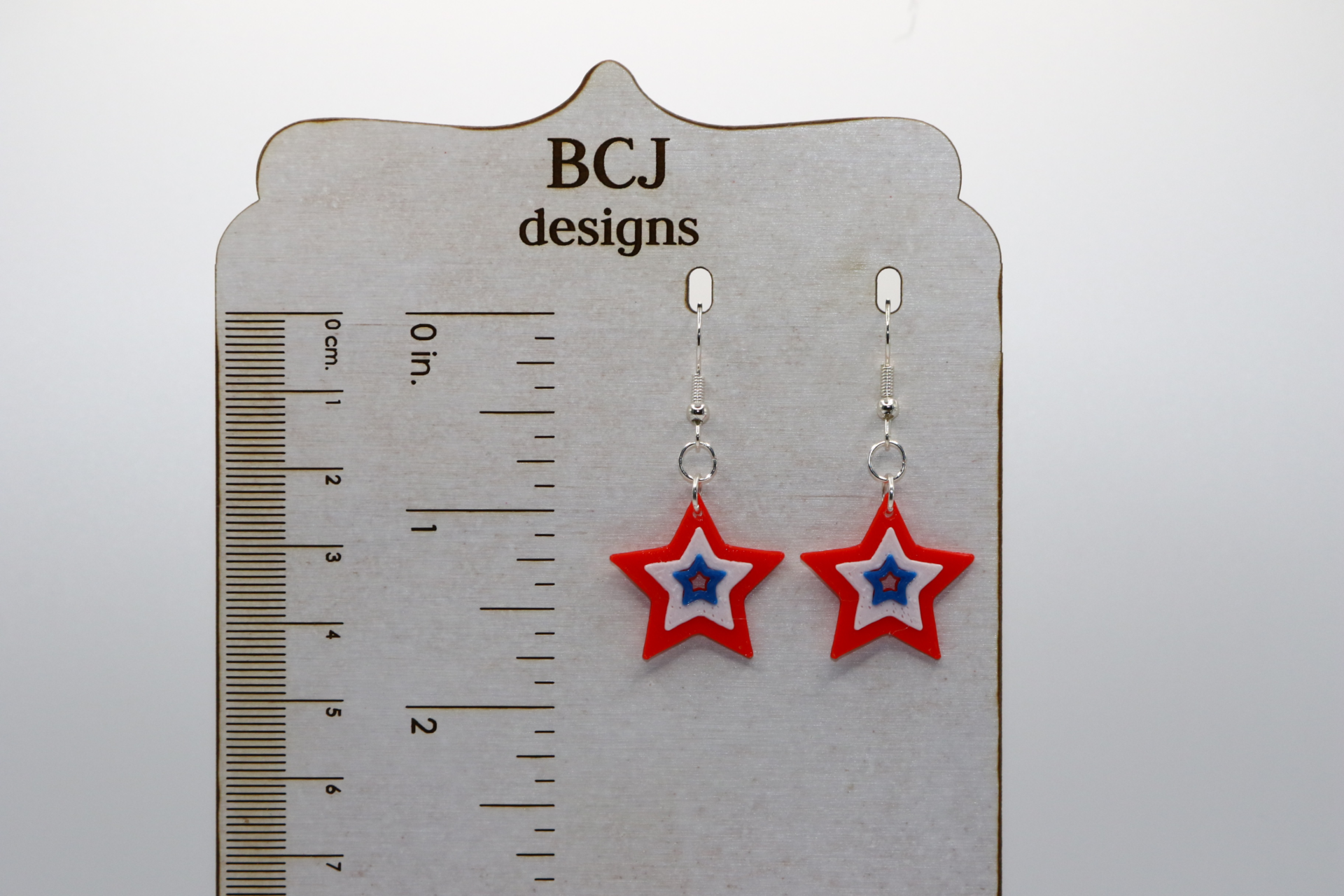 Pair of red, white, and blue star-shaped earrings with glossy finish.