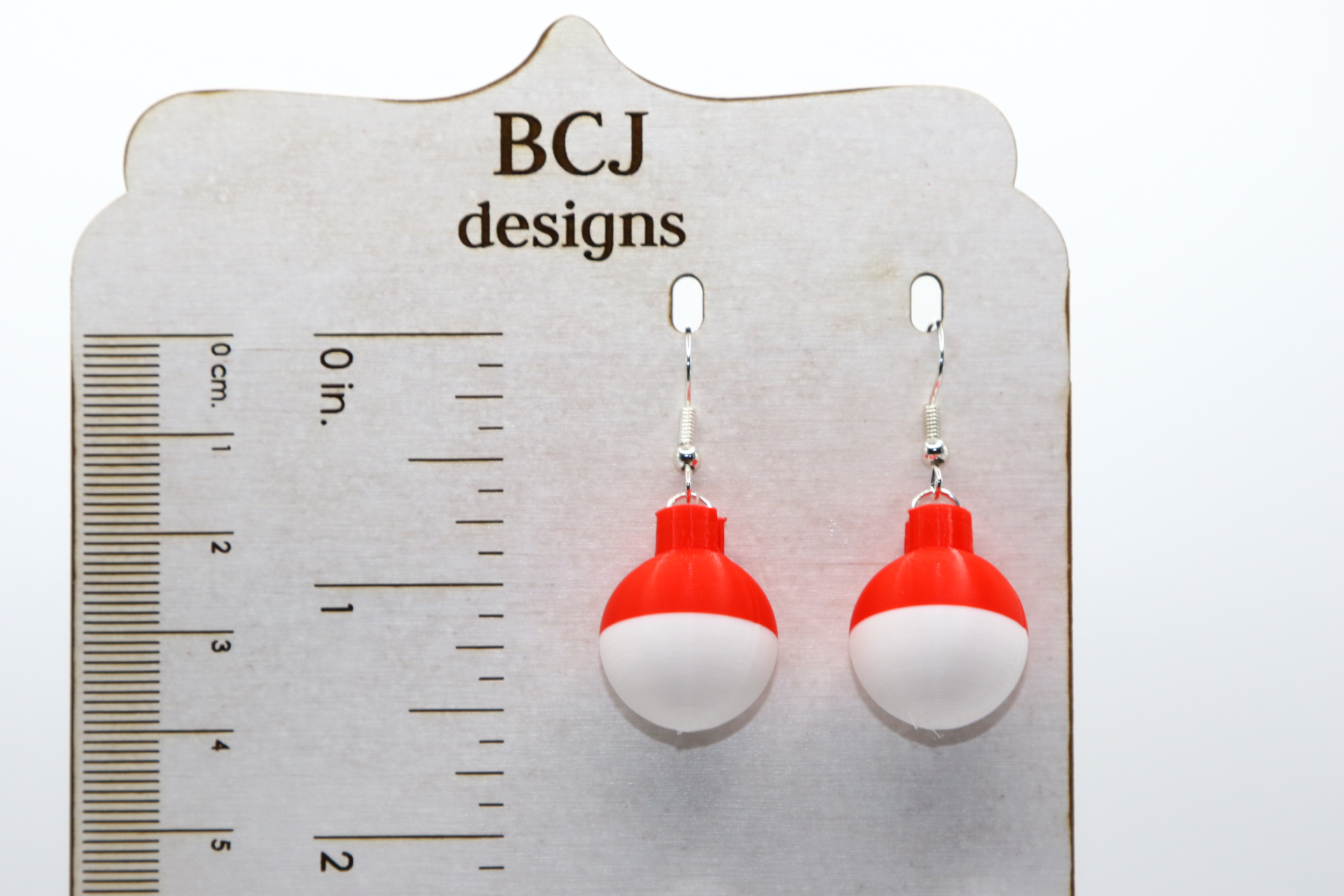 Pair of earrings shaped like red and white fishing bobbers with silver hooks.