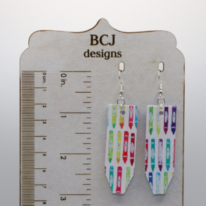 Pair of earrings shaped like colorful faux leather pencils with silver hooks.