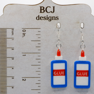 Pair of earrings shaped like a classic glue bottle with white and red details.