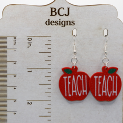 Pair of earrings shaped like red apples with the word “Teach” in white lettering.