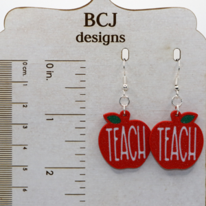 Pair of earrings shaped like red apples with the word “Teach” in white lettering.