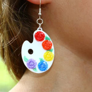 Pair of earrings shaped like painter palettes with multiple colorful paint spots.