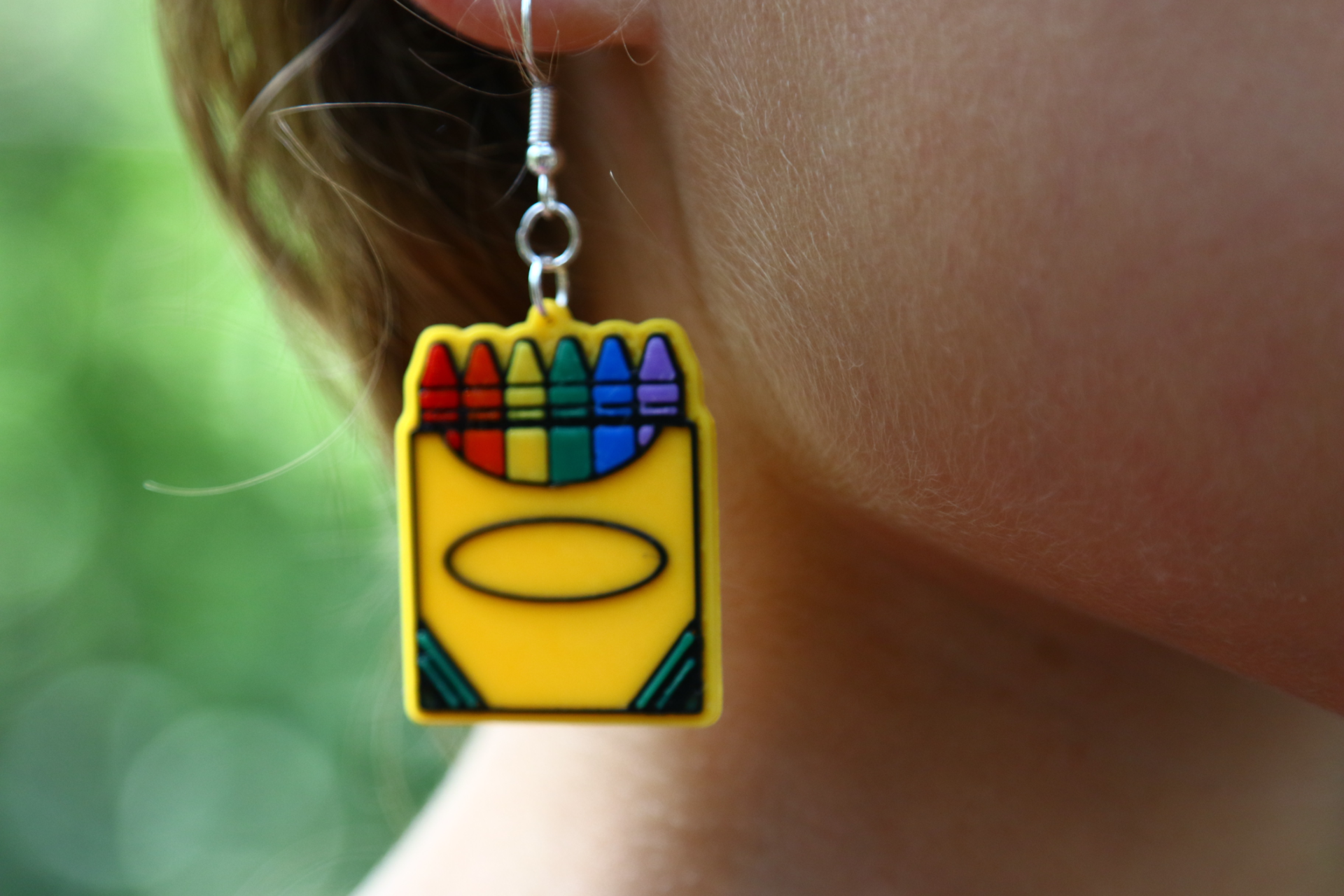 Pair of earrings featuring a colorful box of crayons with multiple hues.