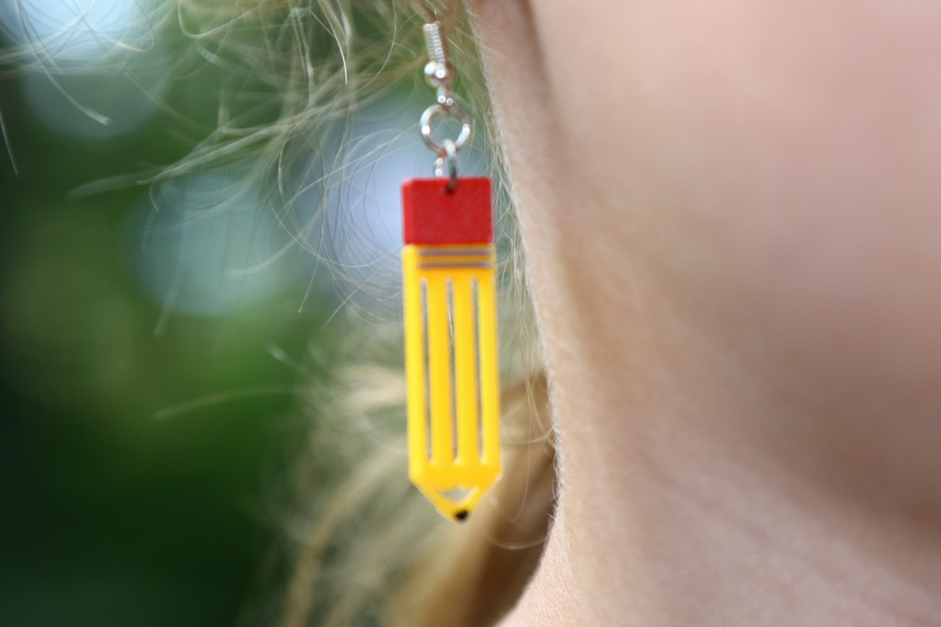 Pair of earrings shaped like yellow pencils with pink erasers and silver hooks.