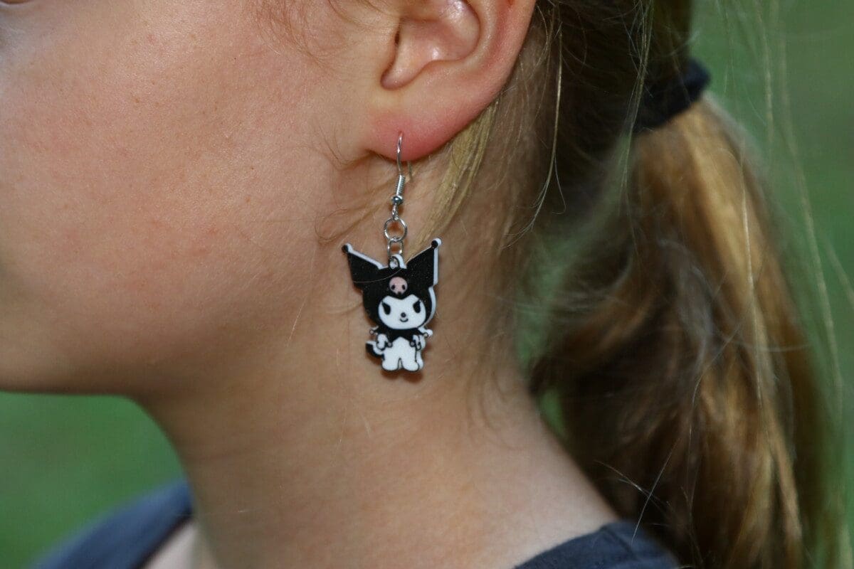Kuromi earrings featuring black jester hat and pink skull detail.