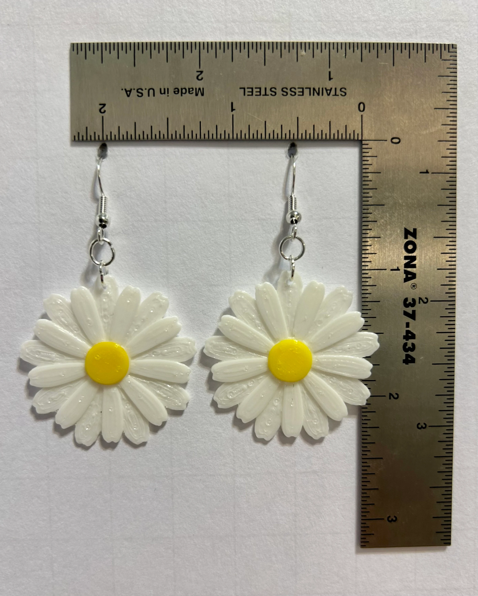 Daisy earrings featuring bright center and detailed petals.